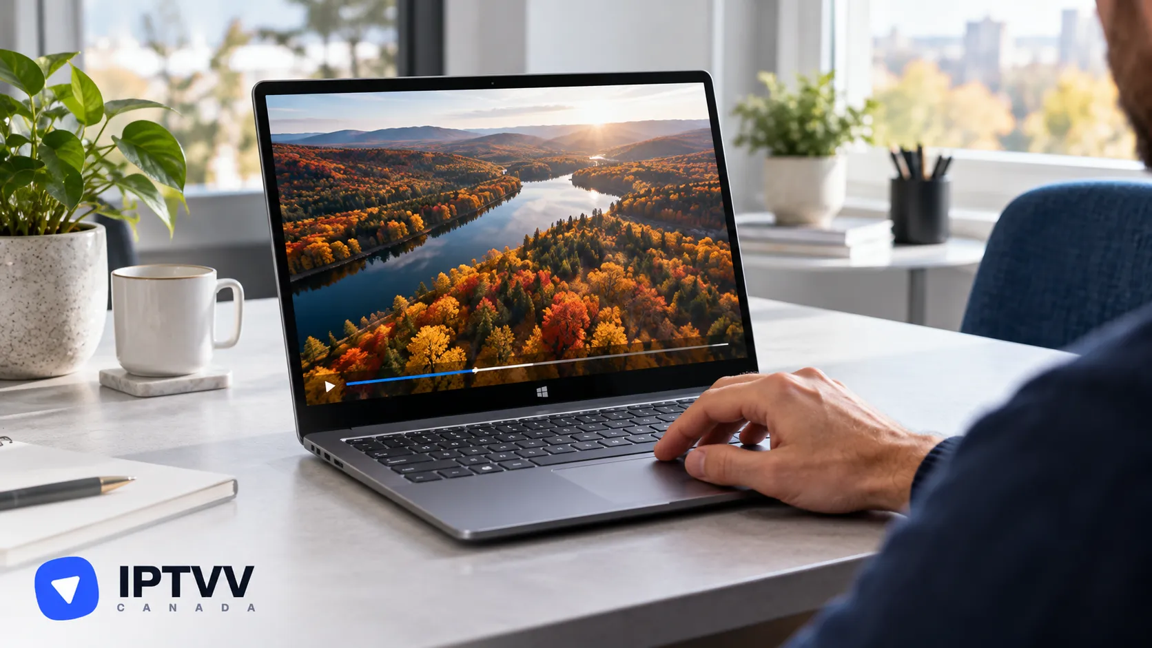 Hands on a Windows laptop playing an aerial video of an autumn forest